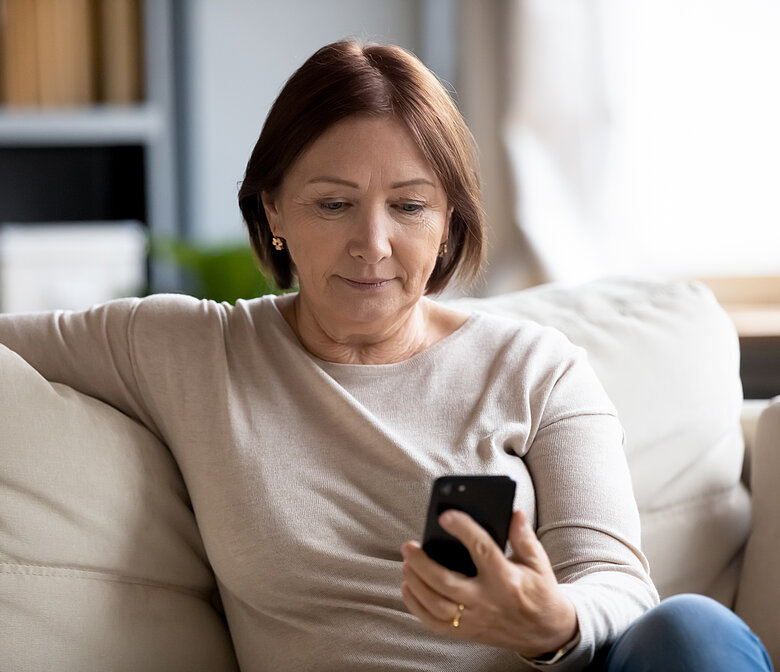 Woman sitting on couch looking at her smartphone