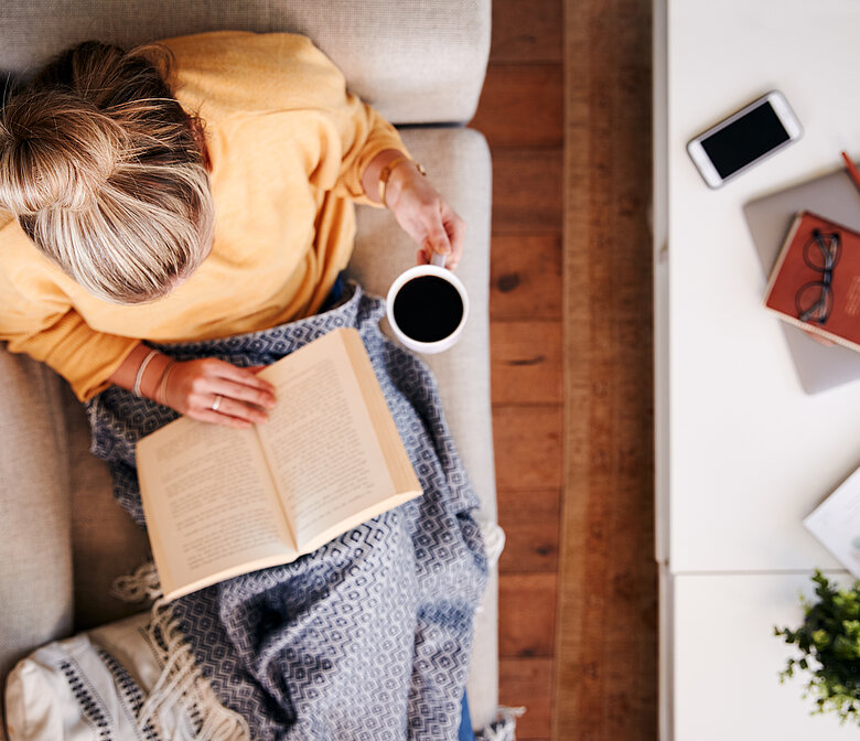 Woman sitting on couch, reading a book